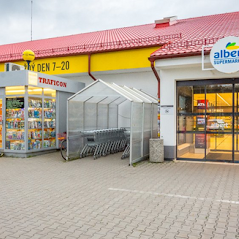 Modulární prodejní stánek s pestrým sortimentem, umístěný před supermarketem Albert.