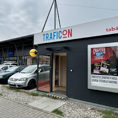 Kompaktní modulární stánek umístěný před supermarketem, nabízející tabák a tiskoviny.